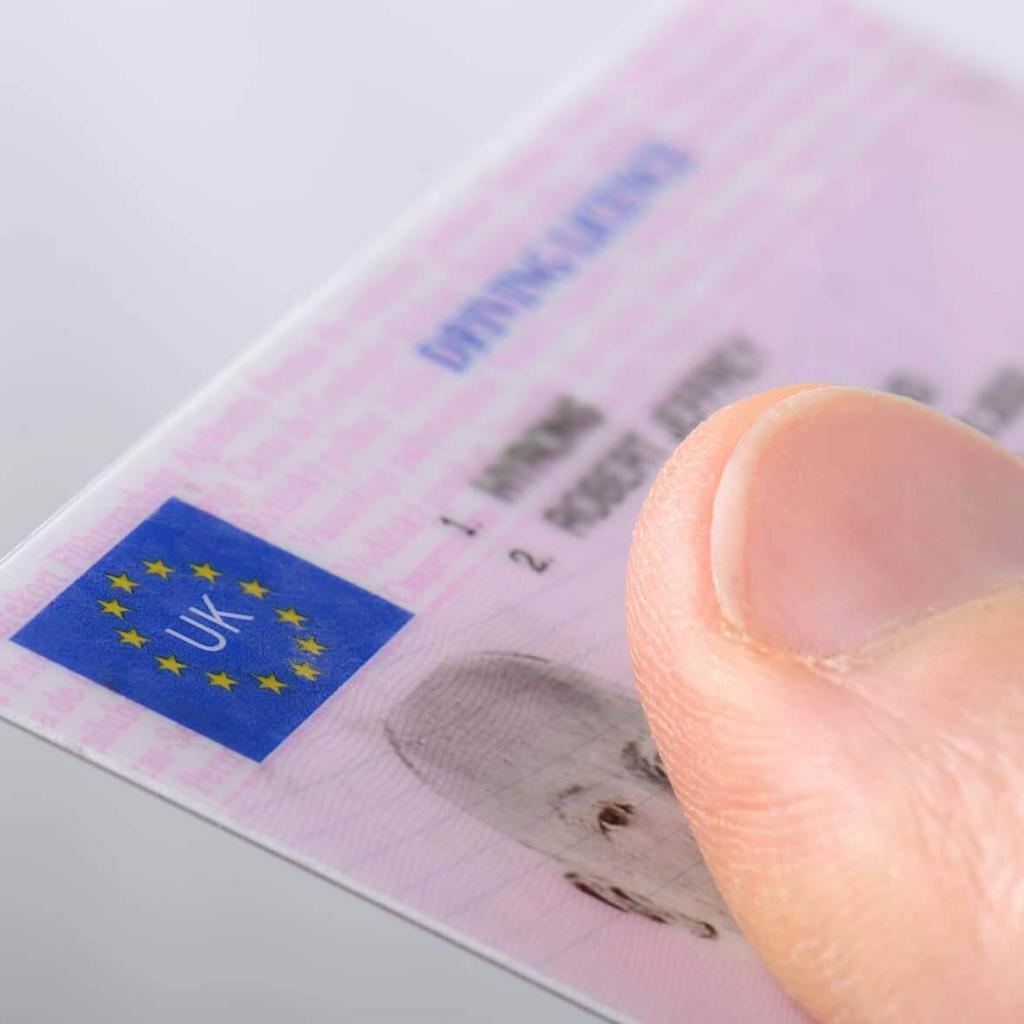 Photo of a thumb holding down on a pink UK driving licence