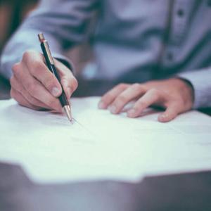 Man writing on paper with a blurry background